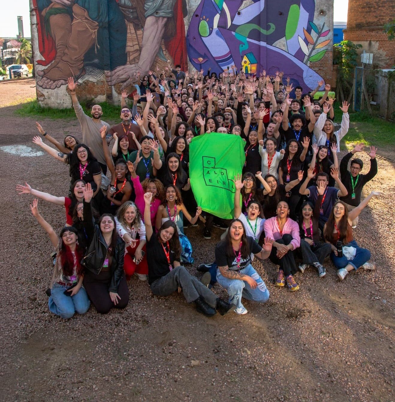Jovens do Geração Caldeira reunidos diante de um mural